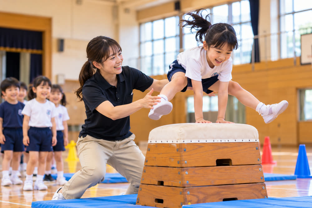 跳び箱を跳ぶ子どもと見守る指導者